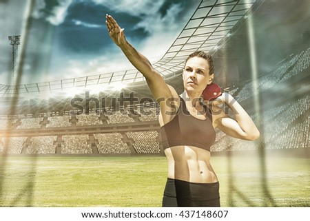 Sportswoman practising the shot put against view of a stadium