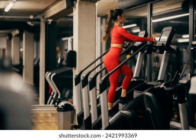 A sportswoman in shape is practicing on stair climbing machine in a gym. - Powered by Shutterstock