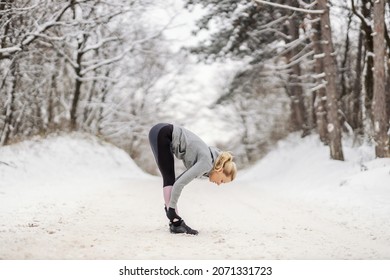 Sportswoman Standing On Snowy Path In Nature At Winter And Doing Stretching And Warmup Exercises. Healthy Life, Winter Fitness, Outdoor Fitness