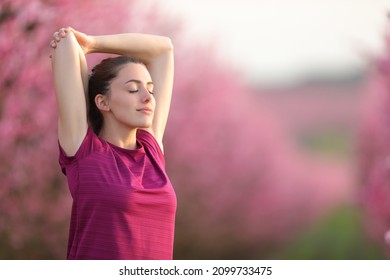 Sportswoman stretching arms and relaxing in a field after sport