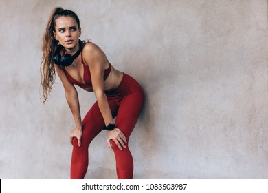 Sportswoman taking break after a run. Focused female athlete standing bend over after a running session. - Powered by Shutterstock