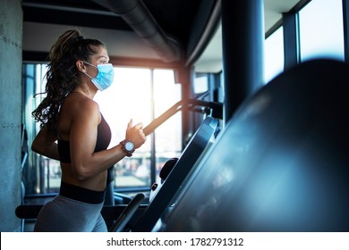 Sportlerin trainiert in Laufband in Fitnessstudio und Tragen Gesichtsmaske, um sich während der globalen Pandemie des Covid-19-Virus gegen Coronavirus zu schützen.