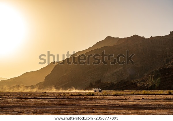 A\
sport-utility vehicle runs in mountains in\
sunset.
