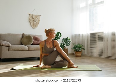 Sporty adult woman practicing yoga in the comfort of her own home. Fit middle aged yogini performing morning physical exercise routine at the living room. Interior background, copy space, close up. - Powered by Shutterstock