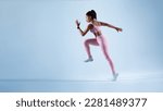 Sporty african american lady running in mid air over blue neon background, panorama with free space. Female runner wearing fitwear during fitness workout. Sport and active life