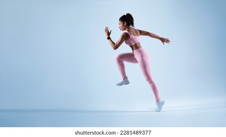 Sporty african american lady running in mid air over blue neon background, panorama with free space. Female runner wearing fitwear during fitness workout. Sport and active life - Powered by Shutterstock