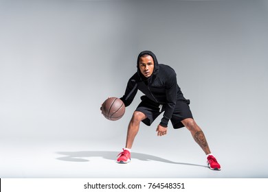 Sporty African American Man Playing With Basketball Ball And Looking At Camera On Grey 