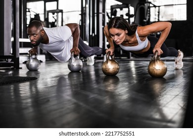 Sporty african man and caucasian woman doing push-up in a gym - Shutterstock ID 2217752551