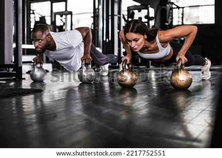 Sporty african man and caucasian woman doing push-up in a gym