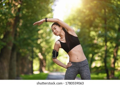 Sporty asian girl exercising before jogging at park, stretching her muscles outdoors, feeling healthy and motivated, copy space - Powered by Shutterstock