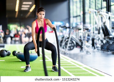 Sporty asian woman exercising with battle ropes at the gym on green floor. Strong female determine with her indoor workout for stamina and building muscular body. Athlete battle rope workout concept. - Shutterstock ID 1513243274