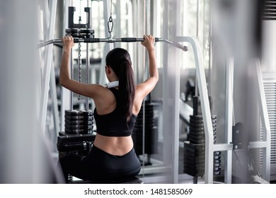 Sporty Asian woman exercising with lat pulldown machine to build arm and shoulder muscle in fitness gym. Bodybuilding and healthy lifestyle concept. - Powered by Shutterstock