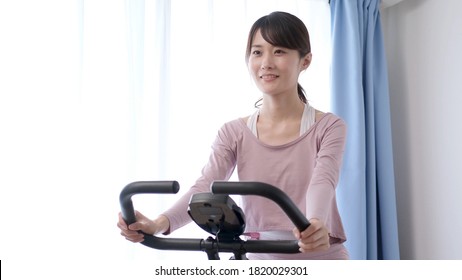 Sporty Asian Woman Riding An Exercise Bike