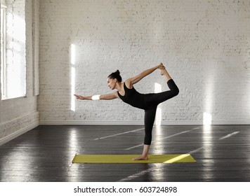 Sporty Asian Young Woman Doing King Dancer Yoga Pose (Natarajasana) At Green Yoga Mat In Training Class In The Morning. Concept Of Healthy Life And Natural Balance Between Body And Mental Development