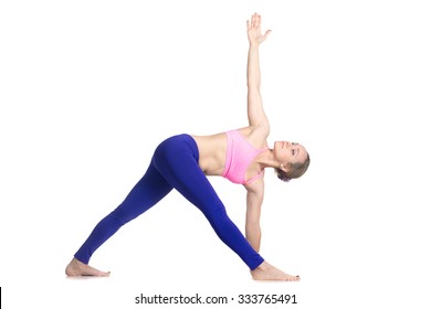 Sporty attractive young blond woman doing side bend, Parivrtta Trikonasana posture, Revolved Triangle Pose, studio full length isolated shot, profile view on white background - Powered by Shutterstock