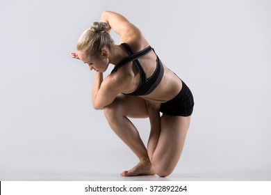 Sporty Beautiful Young Woman Practicing Yoga, Doing Parivrtta Vatayanasana (variation Of Horse Face Pose), Exercise For Knee Joints, Working Out Wearing Black Sportswear, Studio, Full Length