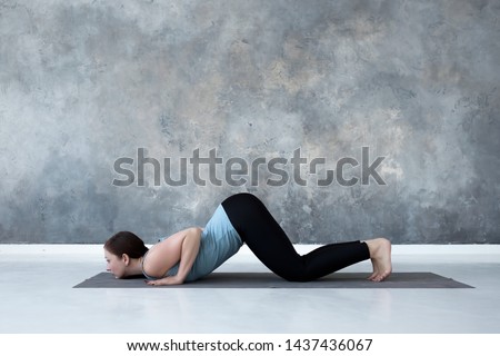 Sporty beautiful young woman practicing yoga, doing half push up or Ashtanga Namaskara from Sun salutation. Side view