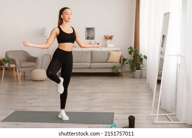 Sporty Black Lady Standing In Balance Yoga Pose On One Leg At Home. Peaceful Fit Woman Meditating With Eyes Closed In Living Room. Mediation, Relaxation And Mindfulness. Full Length