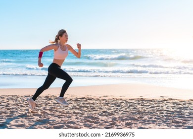 Sporty blonde woman running ocean beach. Young caucasian female exercising outdoors running seashore. Concept of healthy running and outdoors exercise. Active, sporty athlete jogging. Summer active - Powered by Shutterstock