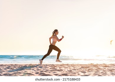 Sporty blonde woman running ocean beach. Young caucasian female exercising outdoors running seashore. Concept of healthy running and outdoors exercise. Active, sporty athlete jogging. Summer active - Powered by Shutterstock