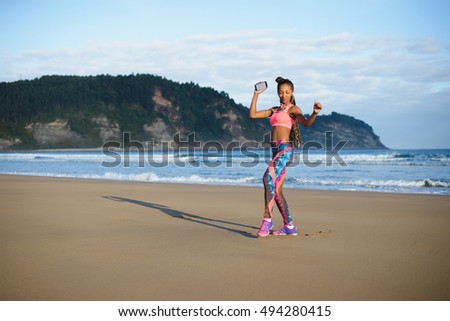 Sporty brazilian woman dancing and having fun at the beach. Black happy dancer enjoying music rhythm.