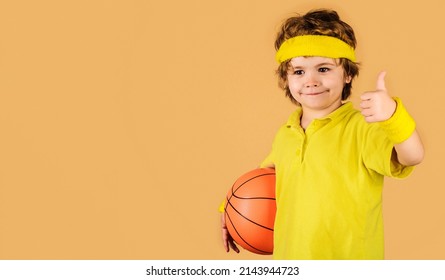 Sporty child with basketball ball showing thumb up. Little basketball player in sportswear.