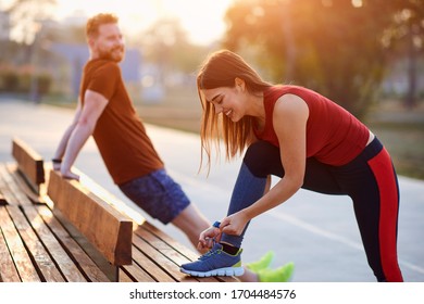 Sporty couple doing exercise in urban area during sunset / sunrise.