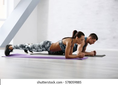 Sporty Couple Doing Plank Exercise In Gym