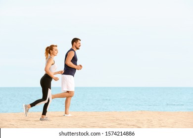 Sporty couple running at sea resort - Shutterstock ID 1574214886