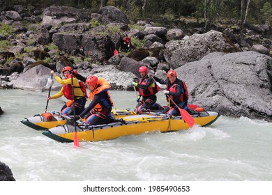 A sporty and dynamic shot of sportsmen rafters on the Katun river. Altai Republic, Russia. Extreme sportsmen in the fast flow of a mountain river in a calm area.