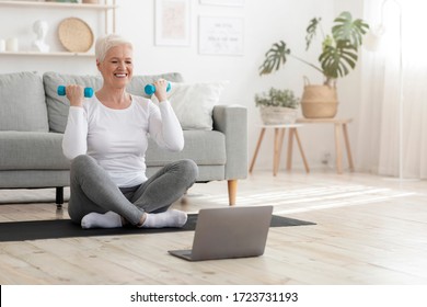 Sporty Elderly Lady Training At Home With Dumbbells, Watching Online Tutorials On Laptop, Copy Space