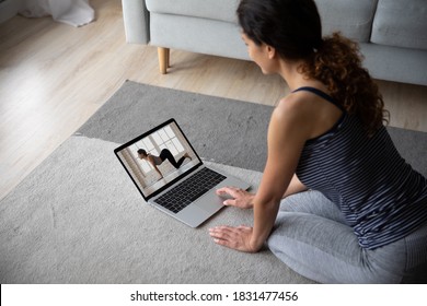 Sporty female sit on floor at home watch video training on computer, take online class or course. Woman practice yoga mediate on video call or webcam digital virtual lesson with private instructor. - Powered by Shutterstock