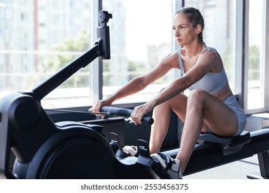 Sporty female using a rowing machine during cross fit training. Female athlete exercising intensely in the gym. High quality photo - Powered by Shutterstock