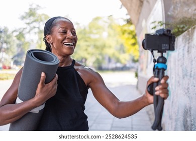 Sporty female vlogger holding her camera and exercise mat in the city
 - Powered by Shutterstock