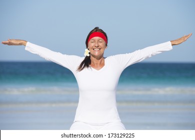 Sporty and fit attractive senior woman sitting relaxed and happy smiling on gymnastic ball at beach after exercising, ocean and blue sky as background and copy space. - Powered by Shutterstock