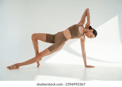 Sporty fitness exercises. Young woman is doing yoga indoors against white background. - Powered by Shutterstock