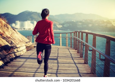 sporty fitness woman runner running on seaside boardwalk