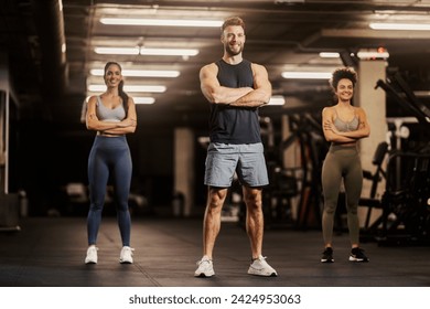 Sporty friends confidently standing in a gym with arms folded. - Powered by Shutterstock