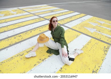 Sporty Ginger Girl Wearing Fashion Sport Chic Clothes Sitting On Street Zebra Crossing Road, Outdoor Shoot, Urban Style. Female Model In Swag Clothes Posing Outside Over Pedestrian Crosswalk.

