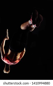 The sporty girl carries out difficult exercise, sports gymnastics. Ring dip Crossfit exercise isolated on black background, high contrast