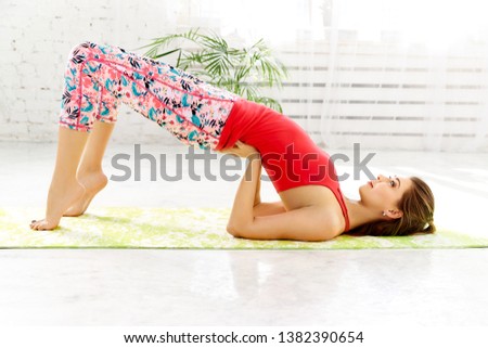 sporty girl doing a bend in the back, standing on toes. Yoga exercise for a healthy spine. Girl lying on her back.