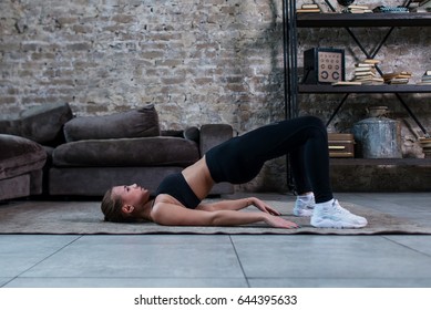 Sporty Girl Doing Floor Hip Raise Or Butt Lift Exercise Lying On Floor In Her Loft Apartment