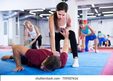 sporty girl is doing self-defence moves with coach in sporty gym.