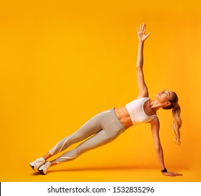 Sporty Girl Doing Side Plank Exercise During Workout Over Yellow Background. Studio Shot