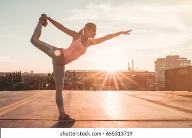 Sporty girl is doing yoga on a sunset. Pose of a swallow.