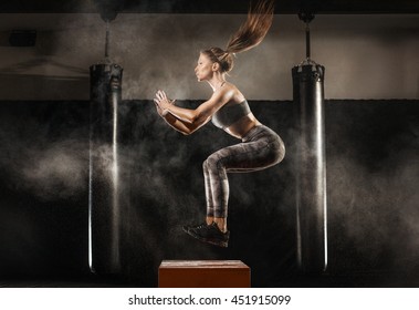 sporty girl jumping over some boxes in a cross-training gym