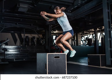Sporty girl jumping over some boxes in a cross-training gym