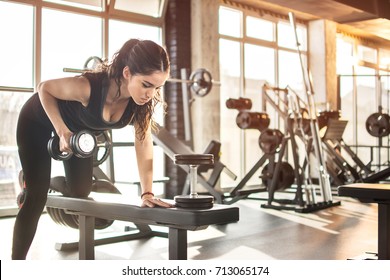 Спортивная девушка поднимает тяжесть в тренажерном зале.