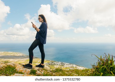sporty girl looks into the smartphone on the mountain on the island of Santorini in Greece