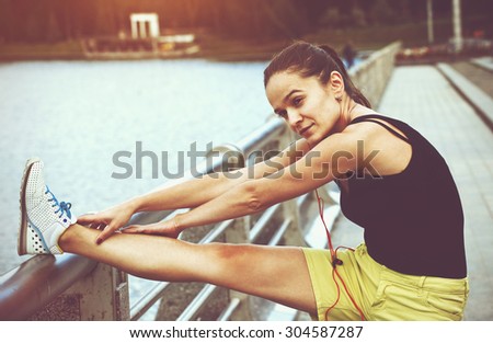 sporty girl making warm-up stretching legs before jogging
